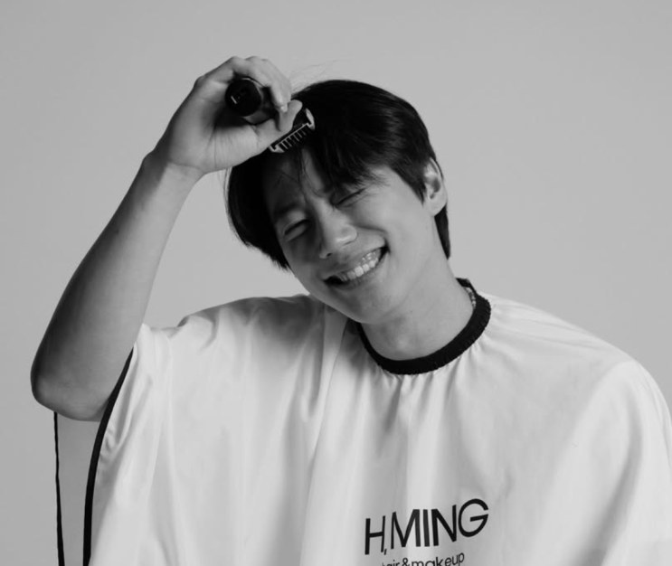 Lee Jun-young rindo, em foto em preto e branco durante uma sessão de cabelo e maquiagem