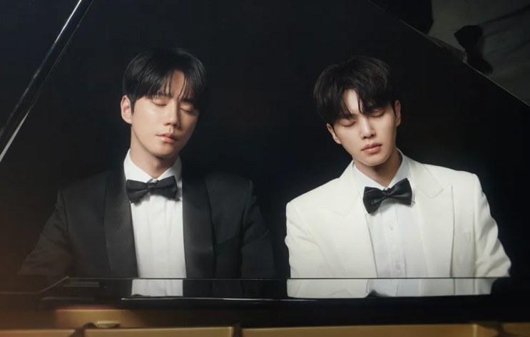 Dois pianistas de smoking ao piano de cauda, em cena de Four Hands, Two Sonatas