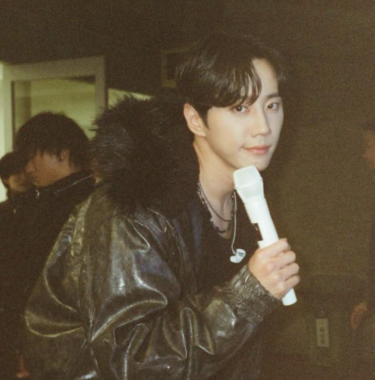 Lee Jun-young com um microfone na mão, nos bastidores de um show