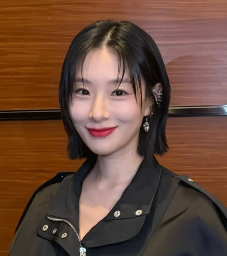 Hyunri sorrindo, de cabelo curto e jaqueta de couro